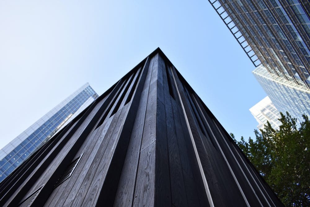 Architectural view of corner of building with charred cladding, looking up