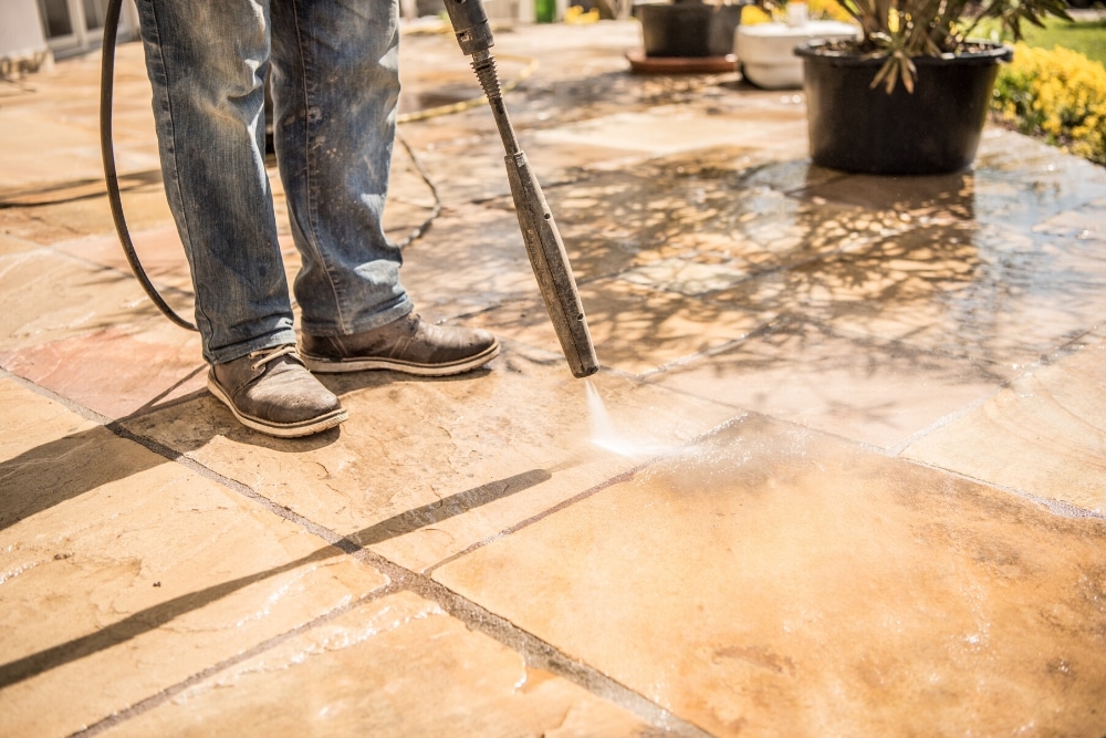 Person using a pressure washer on paving